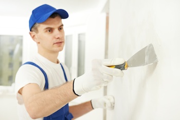 Artisan entrain de rénover un mur avec de l'enduis